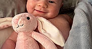 Sydney is registered to the contest to win money with this photo: baby, bed, blanket, child, comfort, cozy, cuddly, cute, face, happy, home, infant, lying_down, pink_bunny, plush_toy, skin, sleepwear, smile, soft, toddler