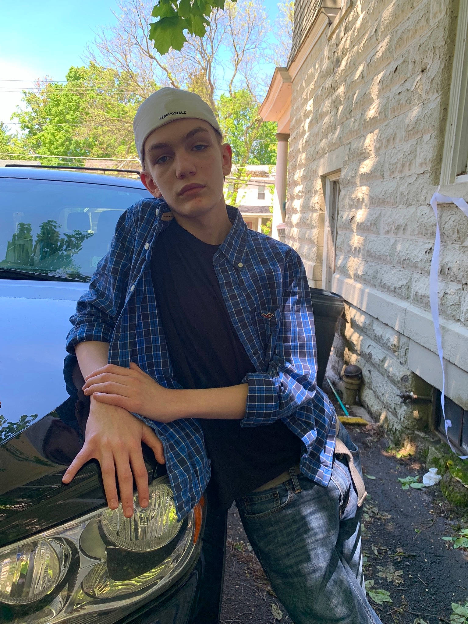 Trent is registered to the contest to win money with this photo: black_hair, cap, cool, denim, headgear, headwear, jeans, male, person, photo_shoot, photography, plant, sitting, smile, t_shirt, textile, vehicle