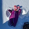 baby, boot, bundled_up, child, cold, cute, infant, mittens, outdoors, pink_hat, play, pom_poms, portrait, purple, shadow, snow, snow_angel, snowsuit, snowy_ground, winter_hat