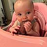 Harlow is registered to the contest to win money with this photo: baby, big_eyes, chewing, closeup, curious, eating, face, feeding, hands, highchair, home_interior, indoor, infant, meat, pink, portrait, seat, skin, television, tray
