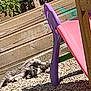 cat, outdoor, gravel, sunlight, wooden_fence, purple_chair, pink_chair, shadow, relaxing, pet, animal, daylight, nature, play_area, resting, summer, feline, colorful, garden, sunbathing