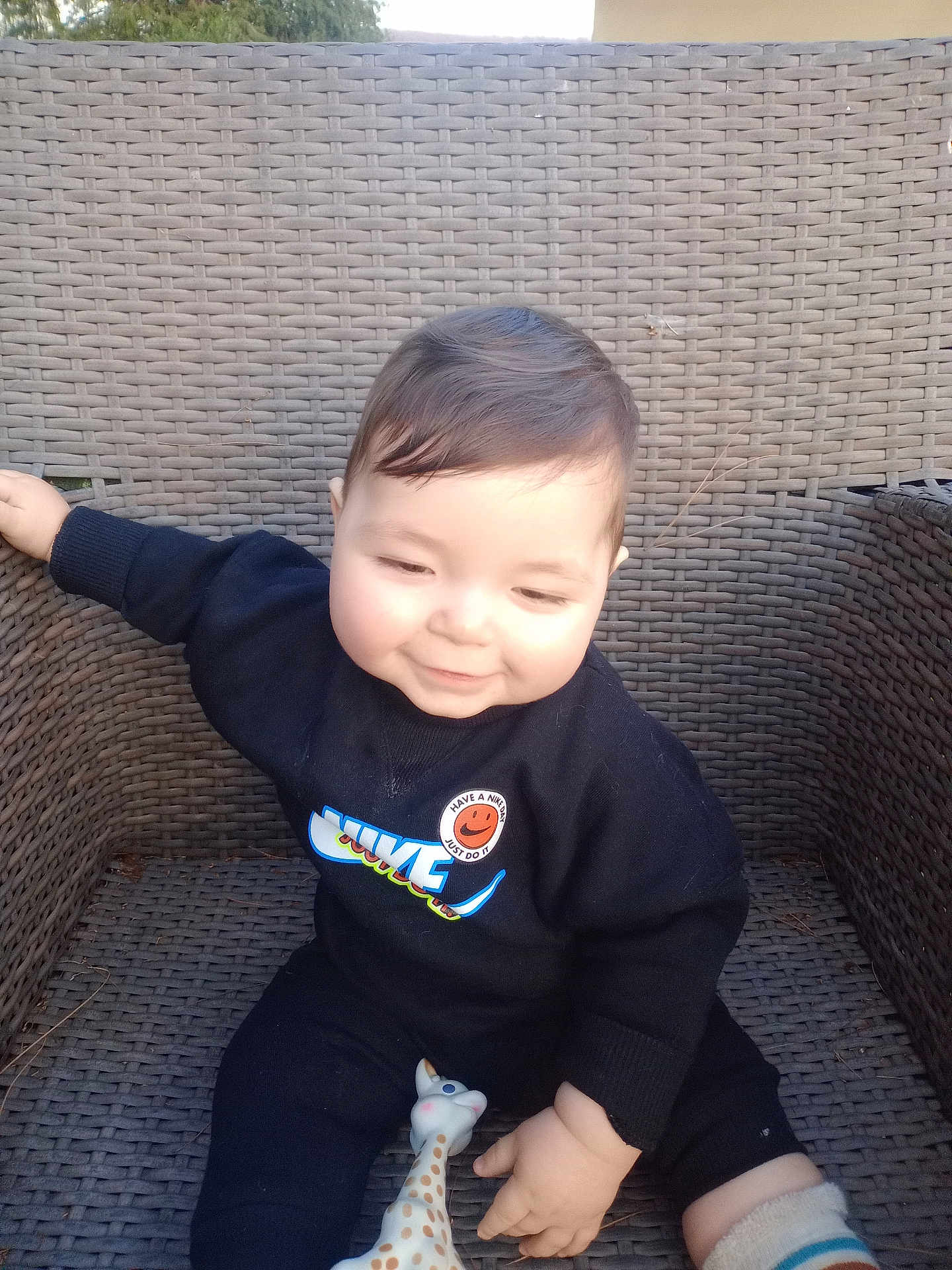 Samaël participe au concours pour gagner de l'argent avec cette photo : baby, child, smile, black_clothing, nike_logo, sweater, giraffe_toy, woven_chair, outdoor, sunlight, happy, cute, infant, playful, sitting, toy, person, portrait, casual, cozy