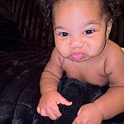 Khyaire is registered to the contest to win money with this photo: adorable, baby, black_blanket, child, curly_hair, cute, earring, expression, face, hands, indoor, infant, plush_couch, portrait, puckered_lips, relaxed, skin, smiling, soft_texture, young