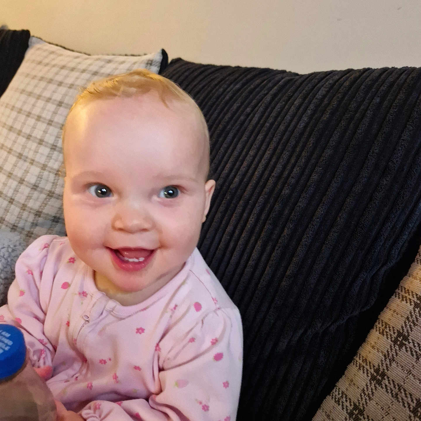 Layla is registered to the contest to win money with this photo: baby, bottle, child, comfort, couch, cozy, cute, expression, face, hand, happy, home, indoor, infant, pillow, pink_clothing, portrait, seated, smile, young_child