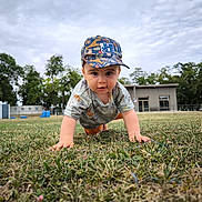 Camille a rejoint le concours — aidez-le/la à gagner de superbes lots ! toddler, child, grass, outdoor, crawling, cap, shirt, nature, trees, building, sky, cloudy, curious, baby, person, young_child, play, park, greenery, daytime
