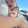 baby, child, person, smile, happy, arm, skin, tattoo, clothing, striped, blue_eyes, sunlight, daylight, car_interior, window, adult, holding, closeup, portrait, outdoor