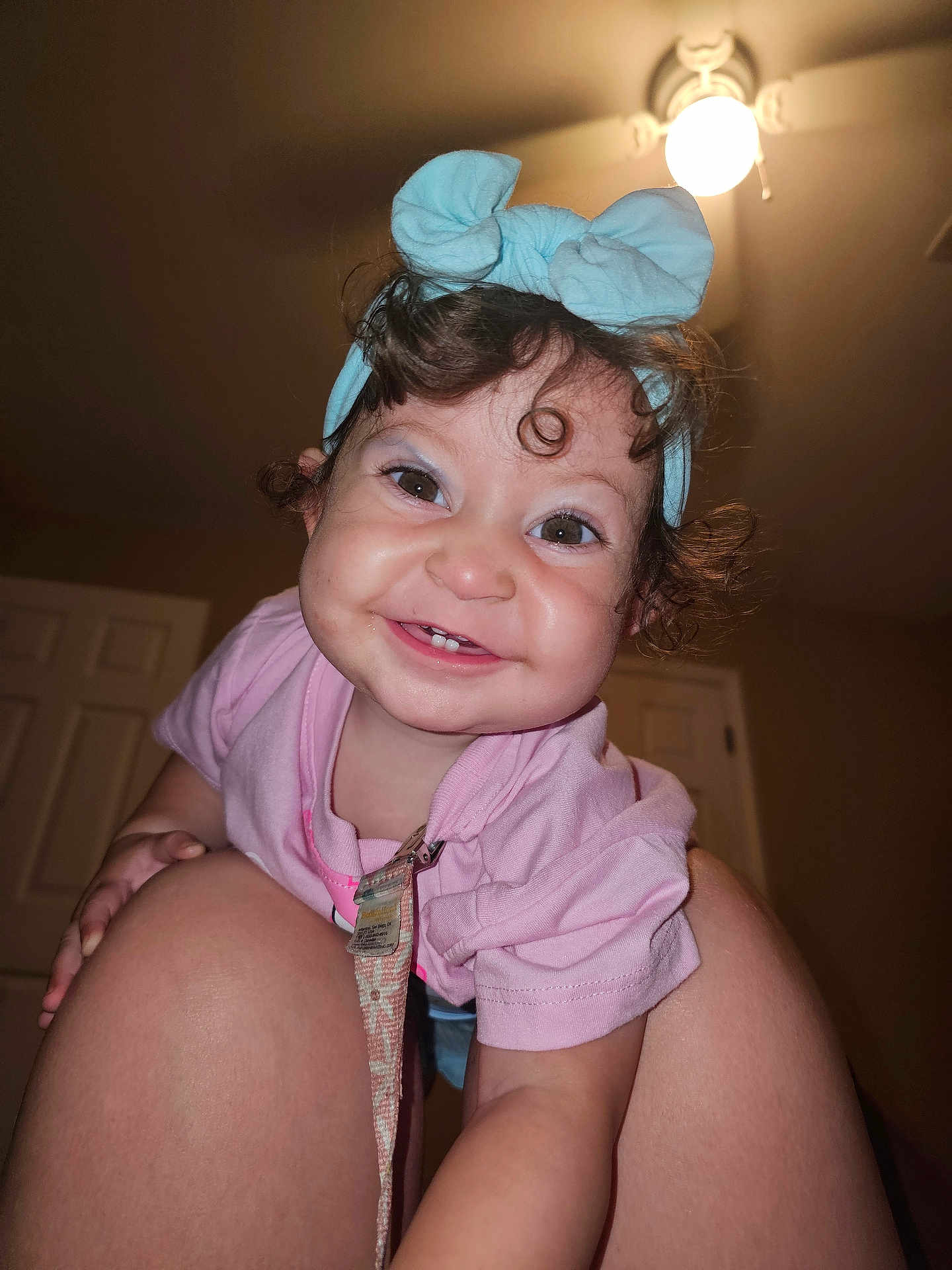 Ziora is registered to the contest to win money with this photo: toddler, child, smiling, curly_hair, headband, blue_headband, pink_shirt, indoor, ceiling_light, knees, happy, person, cute, baby, face, portrait, room, human, closeup, playful