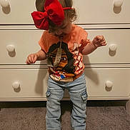 Ziora is registered to the contest to win money with this photo: toddler, child, red_bow, pacifier, jeans, tshirt, shoes, standing, carpet, dresser, indoors, clothing, baby, cute, headwear, room, furniture, person, young_child, casual
