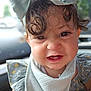 Ziora is registered to the contest to win money with this photo: child, toddler, baby, face, curly_hair, bow, headwear, bib, clothing, smiling, expression, portrait, cute, indoors, natural_light, skin, eyes, mouth, person, closeup