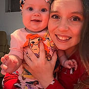 Annabelle is registered to the contest to win money with this photo: baby, woman, smile, indoor, headband, cartoon_characters, pajamas, penguins, holding, happy, child, face, portrait, person, clothing, cute, family, together, warm, joyful