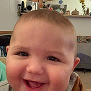 Axel joined the competition — help win amazing prizes! baby, smiling, face, indoor, child, person, joy, happy, closeup, head, cheeks, clothing, sleeves, furniture, decor, flowers, background, living_room, couch, home