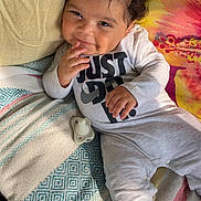 Lorenzo joined the competition — help win amazing prizes! baby, child, curly_hair, onesie, smile, lying_down, blanket, colorful, cheeky, indoors, couch, cozy, cute, happy, infant, person, playful, relaxed, soft_toys, sunlight
