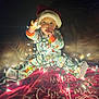baby, child, christmas_lights, santa_hat, pajamas, couch, blanket, holiday, festive, indoors, glowing, cute, curious, face, person, bright, decor, celebration, winter, cozy