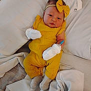 Ashlynn is registered to the contest to win money with this photo: baby, infant, yellow_outfit, headband, bow, mittens, bed, blanket, white_sheets, lying_down, cute, child, person, sock, cozy, indoors, portrait, newborn, fashion, soft_lighting