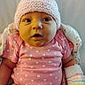 baby, infant, pink_hat, pink_shirt, hearts_pattern, blanket, clothing, face, portrait, cute, child, newborn, wrapped, soft_texture, indoor, skin, expression, wide_eyes, small_hands, cozy