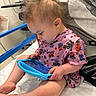baby, bed, blue_rails, cartoon, child, colorful, family_photo, focused, hospital, hospital_bed, indoors, medical_equipment, pajamas, pink_clothing, portrait, side_profile, sitting, tablet, technology, toddler