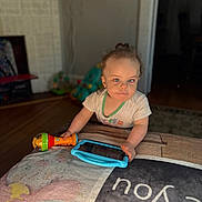 Carley is registered to the contest to win money with this photo: baby, bed, bedroom, blanket, blue_eyes, child, clothing, curly_hair, face, furniture, hands, home, indoors, microphone, portrait, sitting, tablet, technology, toddler, toy