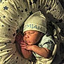 newborn, baby, sleeping, hat, cap, star_pattern, cushion, infant, cozy, blanket, soft_lighting, resting, child, cute, peaceful, portrait, indoors, person, wrapped, sleep