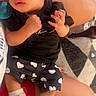 Ariyah is registered to the contest to win money with this photo: baby, child, infant, portrait, sitting, black_outfit, heart_pattern, sneakers, glitter_shoes, fashion, serious_expression, indoor, adult_arms, close_up, face, hands, hair, carpet, colorful, family