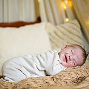Djovan participe au concours pour gagner de l'argent avec cette photo : baby, smiling, sleeping, infant, blanket, knitwear, pillow, cozy, indoors, warm_lighting, soft_texture, cute, happy, child, portrait, relaxed, candid, face, comfort, resting
