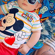 Fraco a rejoint le concours — aidez-le/la à gagner de superbes lots ! baby, child, sunglasses, mickey_mouse, colorful_clothing, blanket, tattoo, foot, hand, indoor, casual, relaxed, cute, person, portrait, toddler, striped_shirt, footwear, pacifier, blue