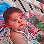 baby, child, infant, playmat, toys, colorful, floral_dress, curious, indoors, cute, face, person, young_child, expression, lying_down, soft_toys, play_area, head, skin, eyes