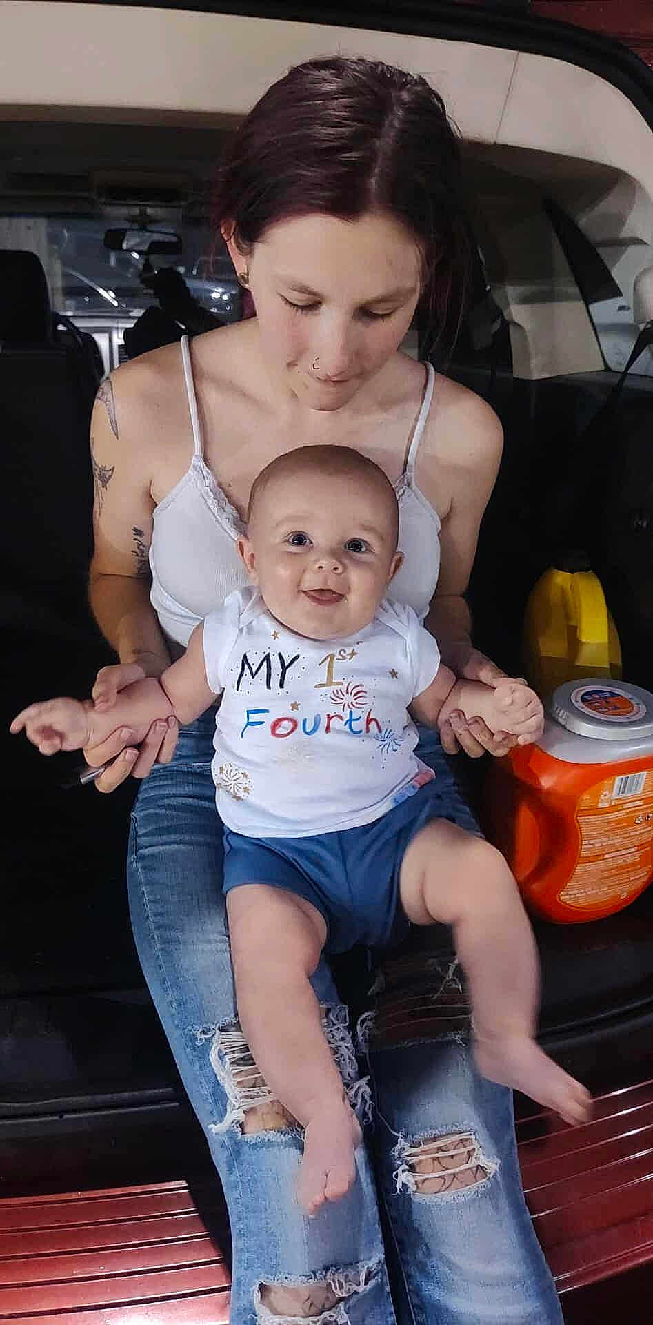 Cassius joined the competition — help win amazing prizes! baby, woman, smile, jeans, tattoo, car_interior, holding_hands, sitting, shirt, happy, infant, ripped_jeans, casual_clothing, person, parent, joyful, indoor, portrait, vehicle, love