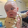 baby, infant, person, clothing, onesie, hand, kitchen, sink, dish_soap, cabinet, facial_expression, curious, indoor, light, holding, cute, soft_lighting, face, eyes, child