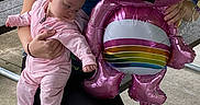 Amaria joined the competition — help win amazing prizes! baby, balloon, bench, casual_clothing, celebration, child, concrete, cute, fun, grass, happy, holding, infant, onesie, outdoor, park, person, pink, rainbow, toy