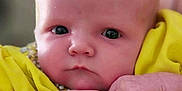 Georgia is registered to the contest to win money with this photo: baby, infant, face, hands, yellow_clothing, portrait, closeup, newborn, cute, skin, expression, young_child, person, soft_background, indoors, small_hands, child, curious_eyes, bright_color, serious_expression