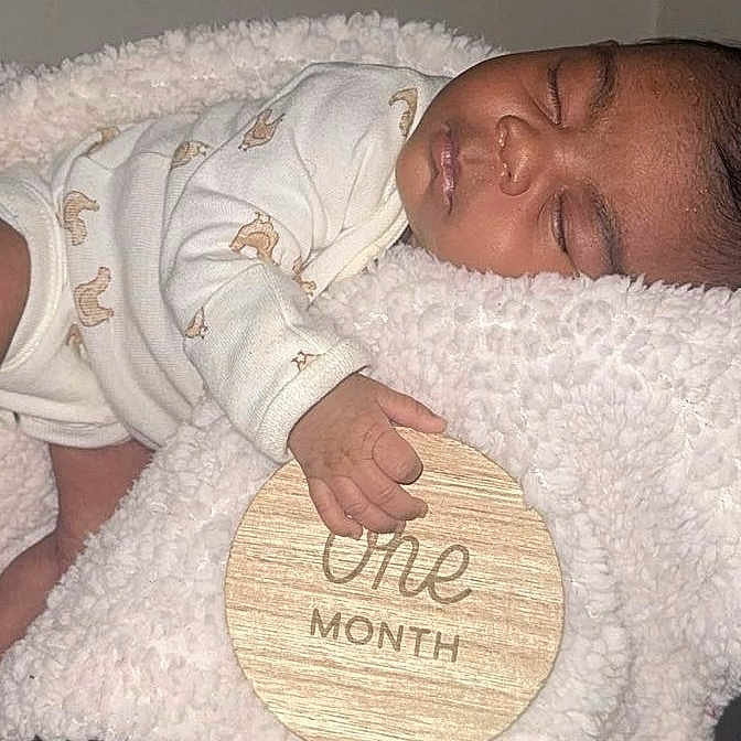 Monay joined the competition — help win amazing prizes! baby, blanket, child, closeup, cozy, cute, face, hand, indoors, infant, newborn, one_month, onesie, peaceful, portrait, resting, sleep, sleeping, soft_texture, wooden_sign