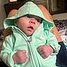 baby, hoodie, mint_green, fists, person, tattoo, legs, indoor, television, furniture, bed, blanket, portrait, child, cute, clothing, infant, expression, young, casual