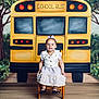 Nevaeh joined the competition — help win amazing prizes! backdrop, bow, chair, child, cute, dress, girl, greenery, happy, indoor, photography, portrait, school_bus, shoes, sitting, smiling, studio, trees, wooden_chair, yellow