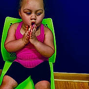 Nevaeh joined the competition — help win amazing prizes! black_shorts, blue_wall, bow, casual_clothing, child, childhood, contemplative, curly_hair, cute, expression, girl, green_chair, hands_together, indoor, pink_tank_top, portrait, sitting, skin_mark, wood_floor, young