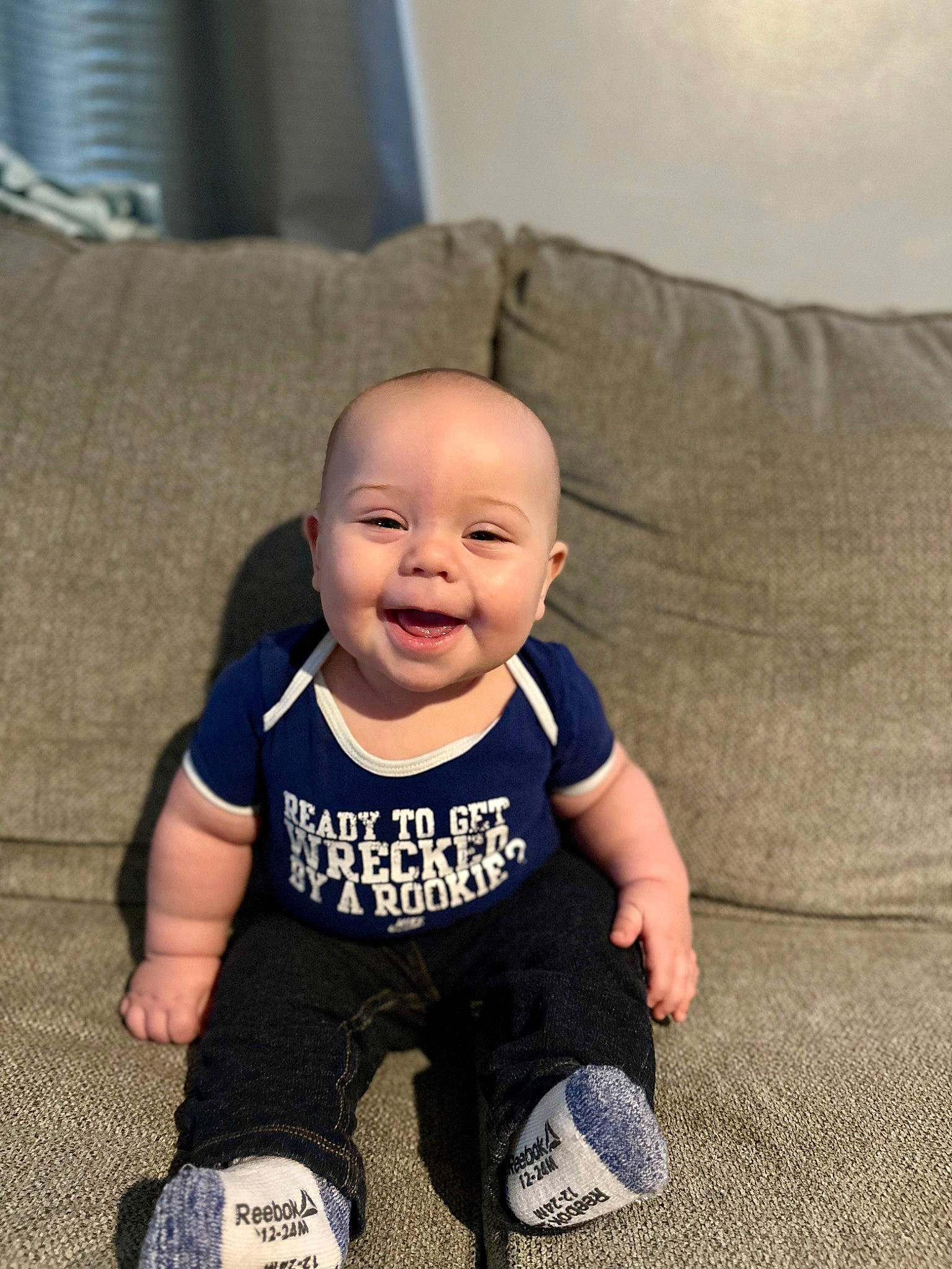 Asher is registered to the contest to win money with this photo: baby, baby_toddler_clothing, child, comfort, couch, eye, floor, flooring, happy, head, joy, living_room, person, room, sitting, sleeve, smile, sportswear, t_shirt, throw_pillow