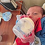Oscar And Oliver is registered to the contest to win money with this photo: baby, newborn, bottle, feeding, hand, blue_clothing, red_napkin, wooden_table, purse, milk, infant, cute, tiny_hands, indoors, person, feeding_bottle, resting, cozy, soft_light, baby_accessories