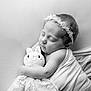 baby, sleeping, black_and_white, blanket, plush_toy, headband, flower, cute, peaceful, infant, portrait, soft_texture, child, adorable, wrapped, tender, face, closed_eyes, resting, newborn