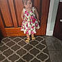 Melody joined the competition — help win amazing prizes! carpet, child, curious, cute, door, dress, floor, floral, girl, hair_ties, indoor, pattern, person, portrait, sandals, standing, tile_floor, toddler, wooden_door, young