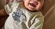 Roman is registered to the contest to win money with this photo: baby, child, infant, smiling, happy, portrait, face, eyes, open_mouth, lying_down, bed, bedspread, pink, clothing, onesie, elephant, toy_design, indoor, close_up, photography