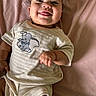 baby, infant, child, smiling, tongue_out, lying_down, portrait, face, pink_blanket, bed, clothing, elephant_design, onesie, short_sleeves, fist, happy, indoor, close_up, soft_lighting, adorable