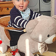 Lowen joined the competition — help win amazing prizes! baby, child, rocking_toy, plush_toy, bear, indoor, smiling, happy, knitted_shoes, striped_sweater, blue_eyes, carpet, wooden_rocker, baby_bib, furniture, laundry_machines, window, curtains, playful, home