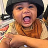 baby, child, smiling, happy, cap, hat, bib, mouth_open, indoor, person, arm, clothing, face, skin, expression, joy, holding, closeup, infant, young