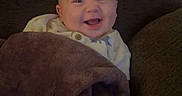 Layne joined the competition — help win amazing prizes! baby, blanket, brown, child, clothing, couch, cozy, eyes, face, happy, head, home, indoors, infant, laughing, mouth, phone_screenshot, portrait, seated, smiling