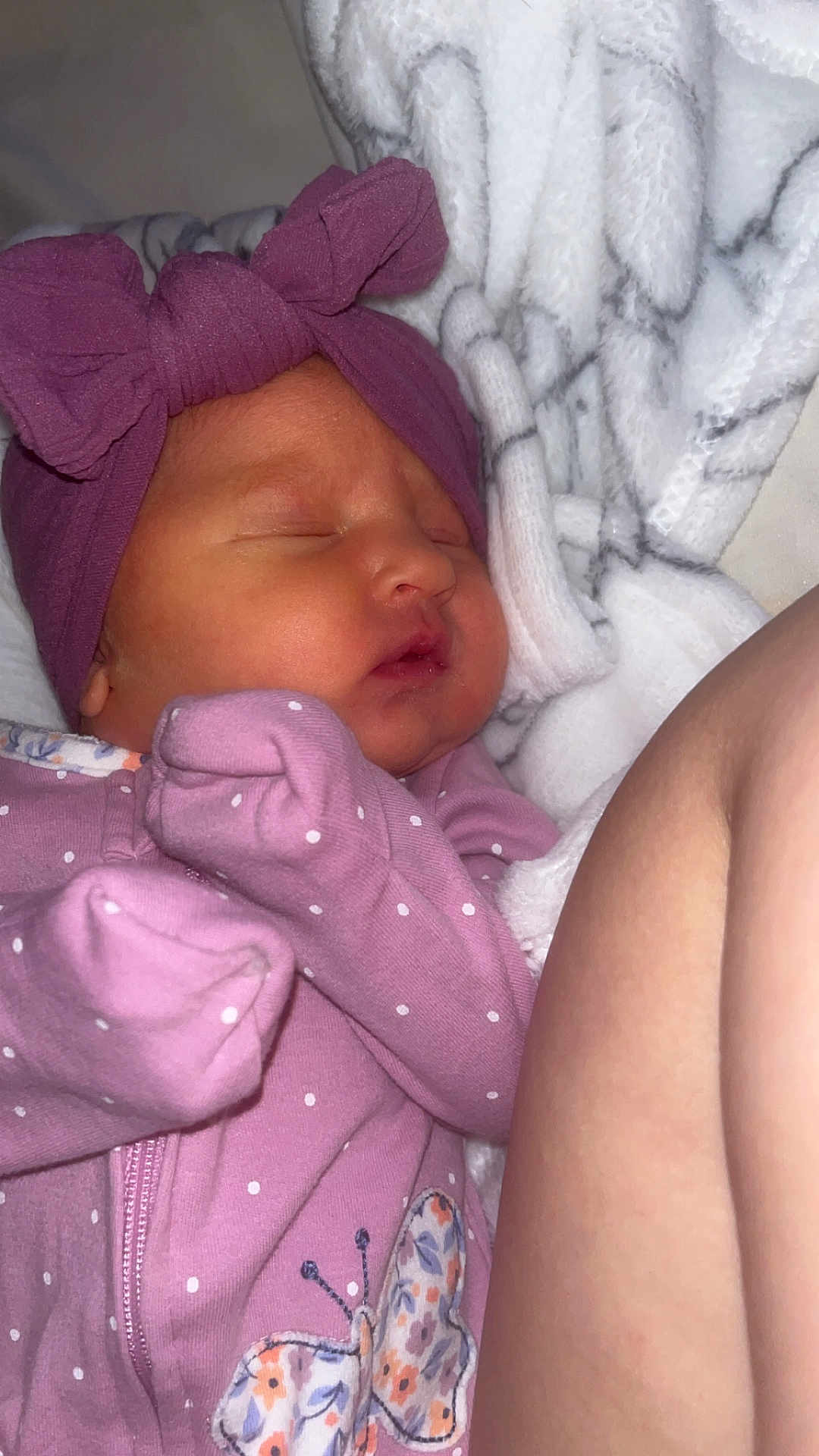 Carmen is registered to the contest to win money with this photo: newborn, baby, sleeping, purple_outfit, headband, bow, blanket, butterfly_patch, infant, cozy, soft, cute, child, face, peaceful, resting, indoors, closeup, skin, person