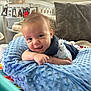 Miller is registered to the contest to win money with this photo: baby, smiling, blue_pillow, infant, indoor, crib, cushion, window, natural_light, happy, face, clothing, person, soft_texture, playful, cute, toddler, home, relaxed, portrait