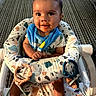 Mark joined the competition — help win amazing prizes! baby, child, infant, bib, toy, highchair, seat, patterned_fabric, carpet, floor, smiling, messy_face, indoor, person, cute, holding, happy, young, playful, colorful