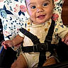 baby, child, infant, smiling, happy, portrait, high_chair, harness, floral, patterned, striped_clothing, bib, overalls, seated, indoors, close_up, brown_hair, baby_teeth, drooling, photography