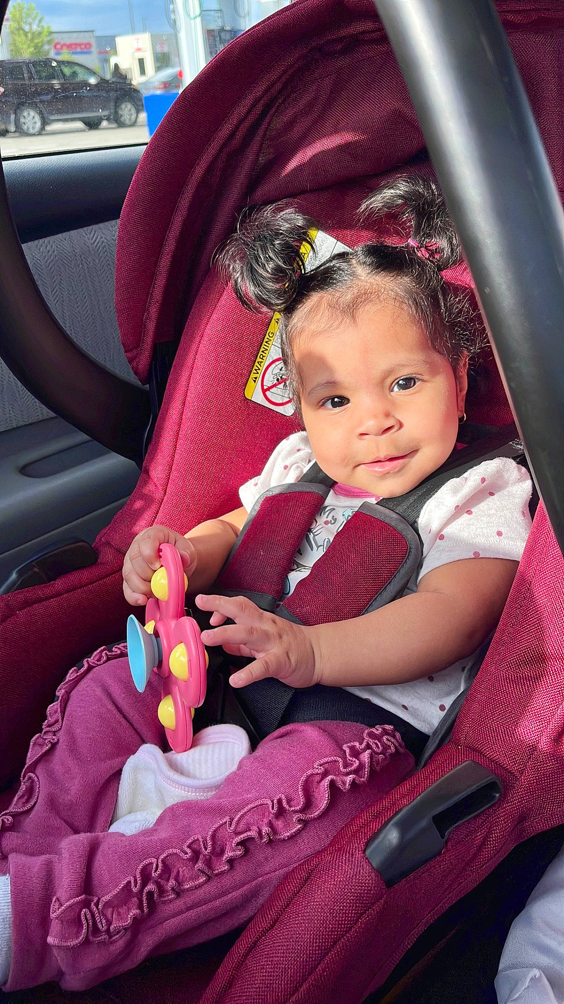 Chloe is registered to the contest to win money with this photo: auto_part, automotive_design, baby_carriage, baby_products, baby_toddler_clothing, car, car_seat, car_seat_cover, child, fun, happy, magenta, motor_vehicle, person, pink, sitting, skin, steering_wheel, toddler, toy