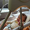 baby, infant, baby_swing, smiling, indoor, sunlight, wooden_floor, couch, seat_belt, graco_brand, happy, child, baby_clothing, living_room, furniture, person, home, comfort, relaxed, daylight