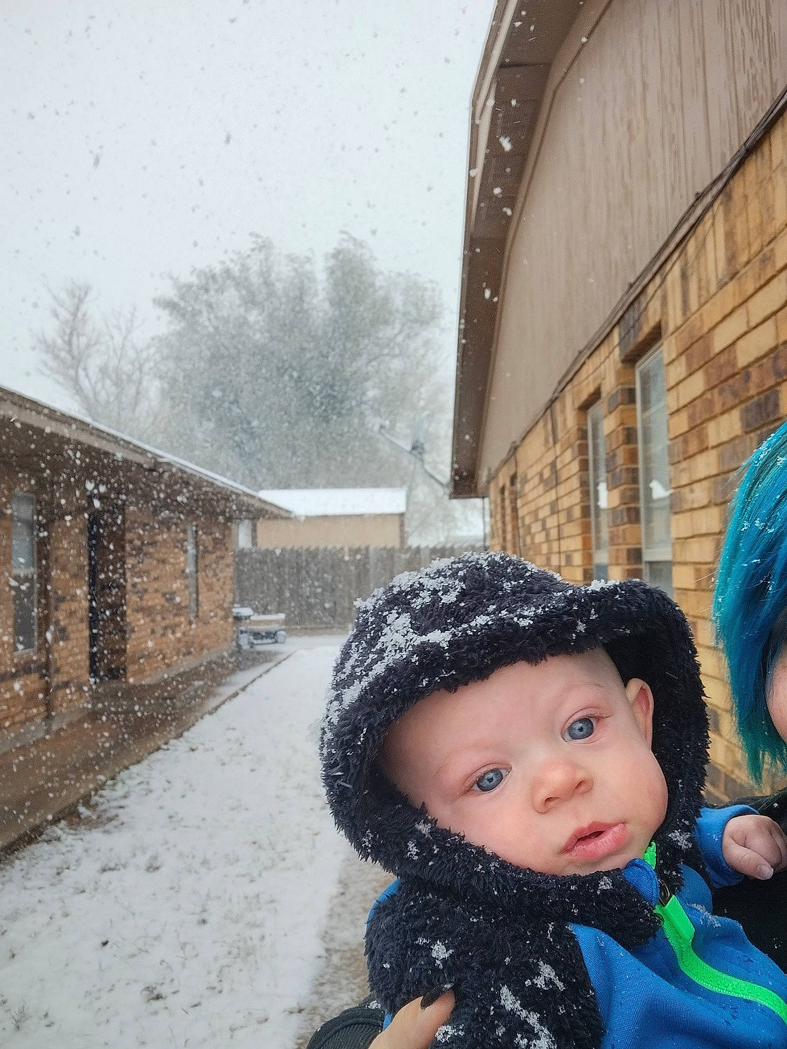 Zachary is registered to the contest to win money with this photo: building, cap, event, fashion_accessory, freezing, frost, fun, fur, headwear, house, leisure, person, personal_protective_equipment, playing_in_the_snow, precipitation, recreation, sky, snow, toddler, tree
